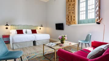 A bedroom with a bed, two bedside tables, a TV, a coffee table with a vase, a chair, and a couch.
