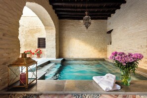 A spa area with a stone pool, a lantern, and a vase of flowers. - Palacio Bucarelli (Seville)