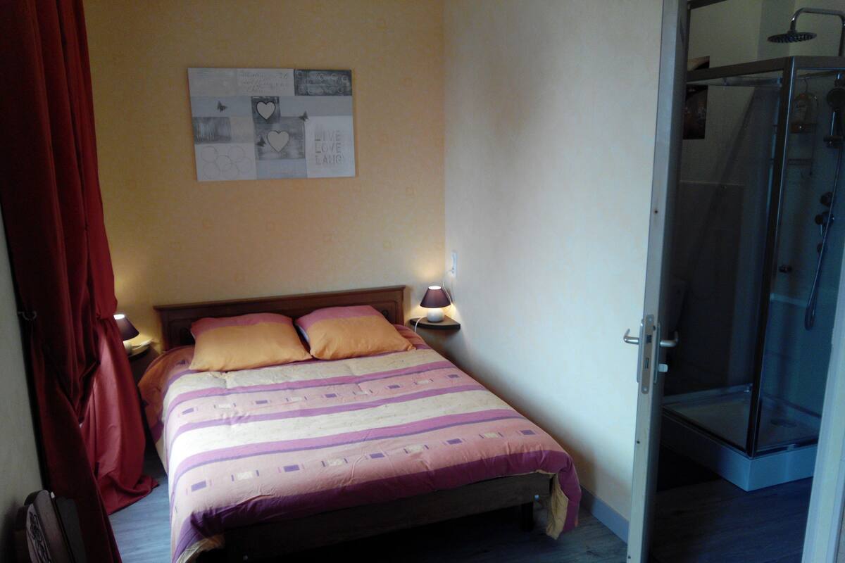 Un dormitorio con cama, dos lámparas de noche, ducha y una pared con un cartel.