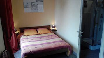 Une chambre à coucher avec un lit, deux lampes de chevet, une douche et un mur orné d’une affiche.