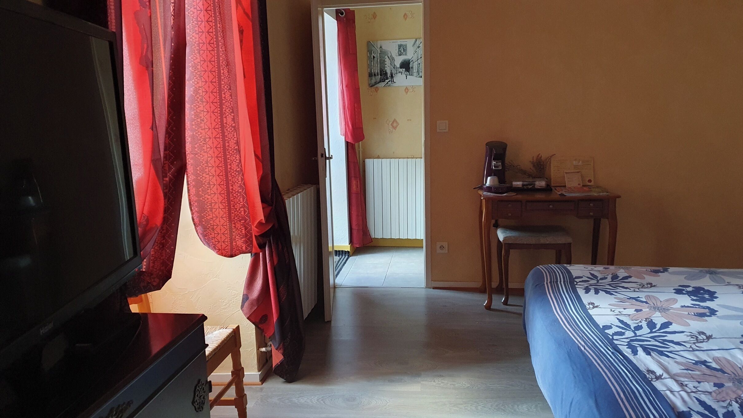 A bedroom with a bed, a desk, a chair, and a television.