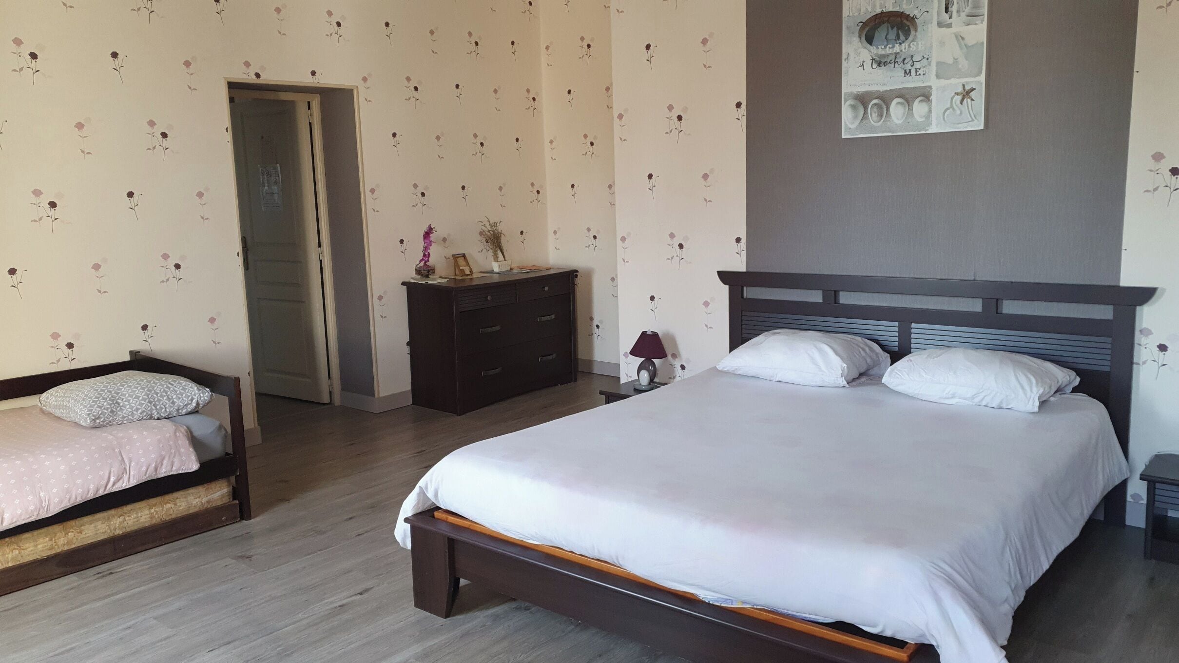 Une chambre à coucher avec un lit, une commode, une table de chevet et une porte.