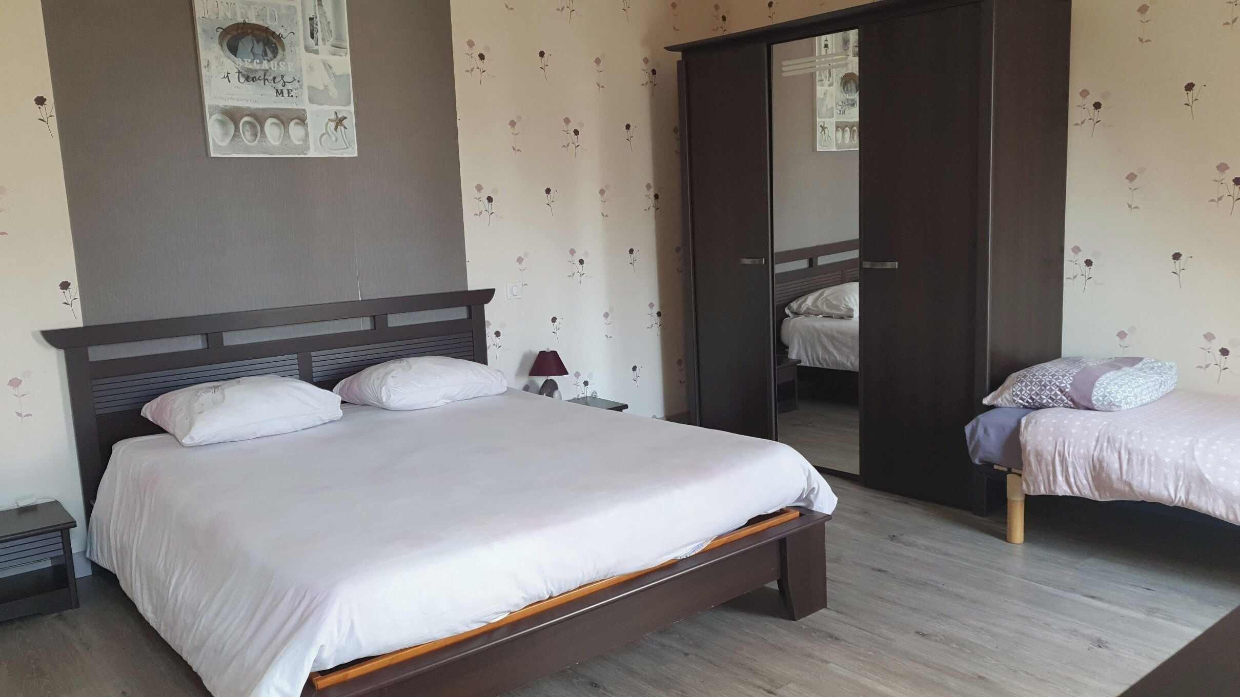 Ein Schlafzimmer mit einem großen Bett, einem Nachttisch, einer Lampe und einem Kleiderschrank.