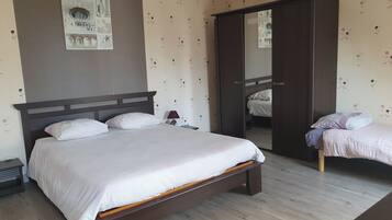 Une chambre à coucher avec un grand lit, une table de chevet, une lampe et une armoire.