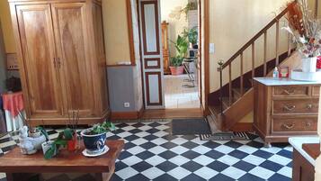 Una habitación con piso a cuadros, muebles de madera, una escalera y vista a otra habitación con plantas.