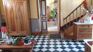 A room with a checkered floor, wooden furniture, a staircase, and a view into another room with plants. - Chambre d'Hôtes Le Clos de Gémozac (Gémozac)