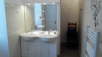 Un baño con dos lavamanos, un espejo y una puerta.