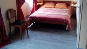 Un dormitorio con una cama, una silla, una mesita de noche y un cartel en la pared.