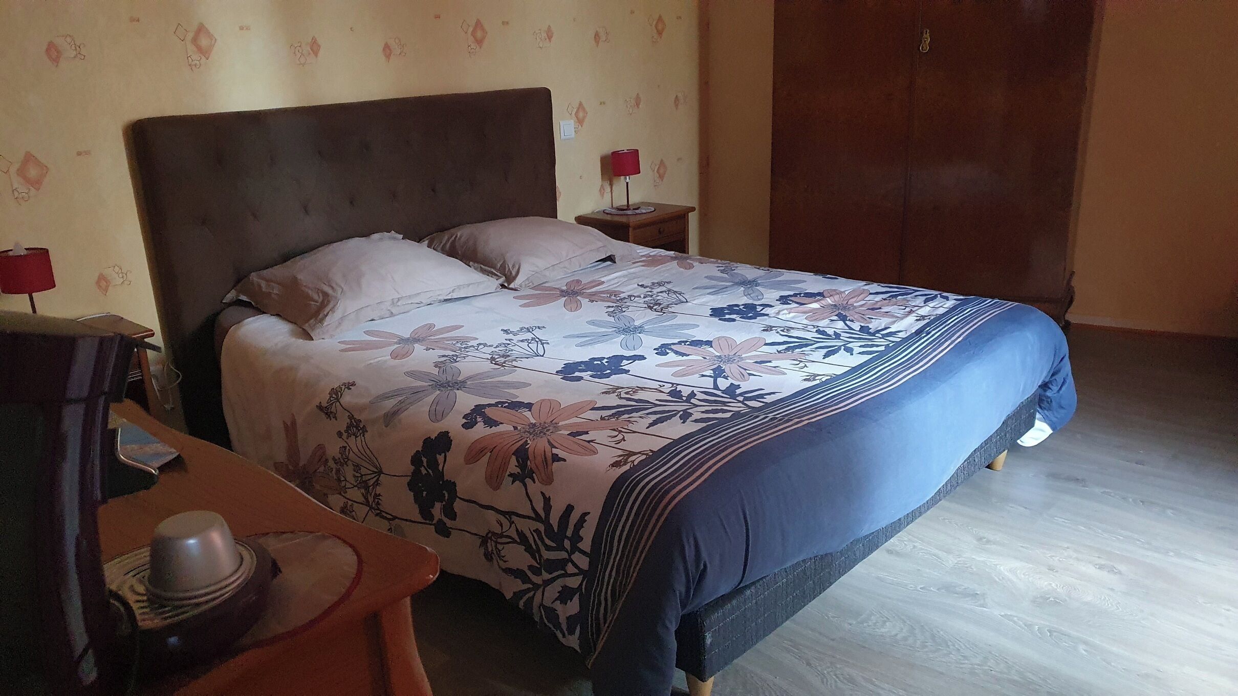 Um quarto com uma cama, duas mesas de cabeceira, um criado-mudo, cômoda e guarda-roupa.