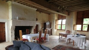 A spacious room with a fireplace, wooden furniture, and large windows. - Le Manoir de la Baronnie (Boischampré)