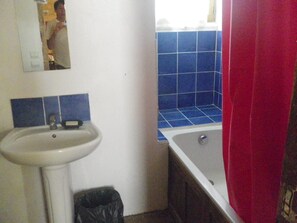 Ein Badezimmer mit einem weißen Waschbecken, blauen Fliesen, einem roten Duschvorhang und einem Spiegel.