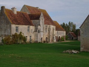 Ein historisches Steinhaus mit mehreren Schornsteinen und einem gepflegten Rasen.