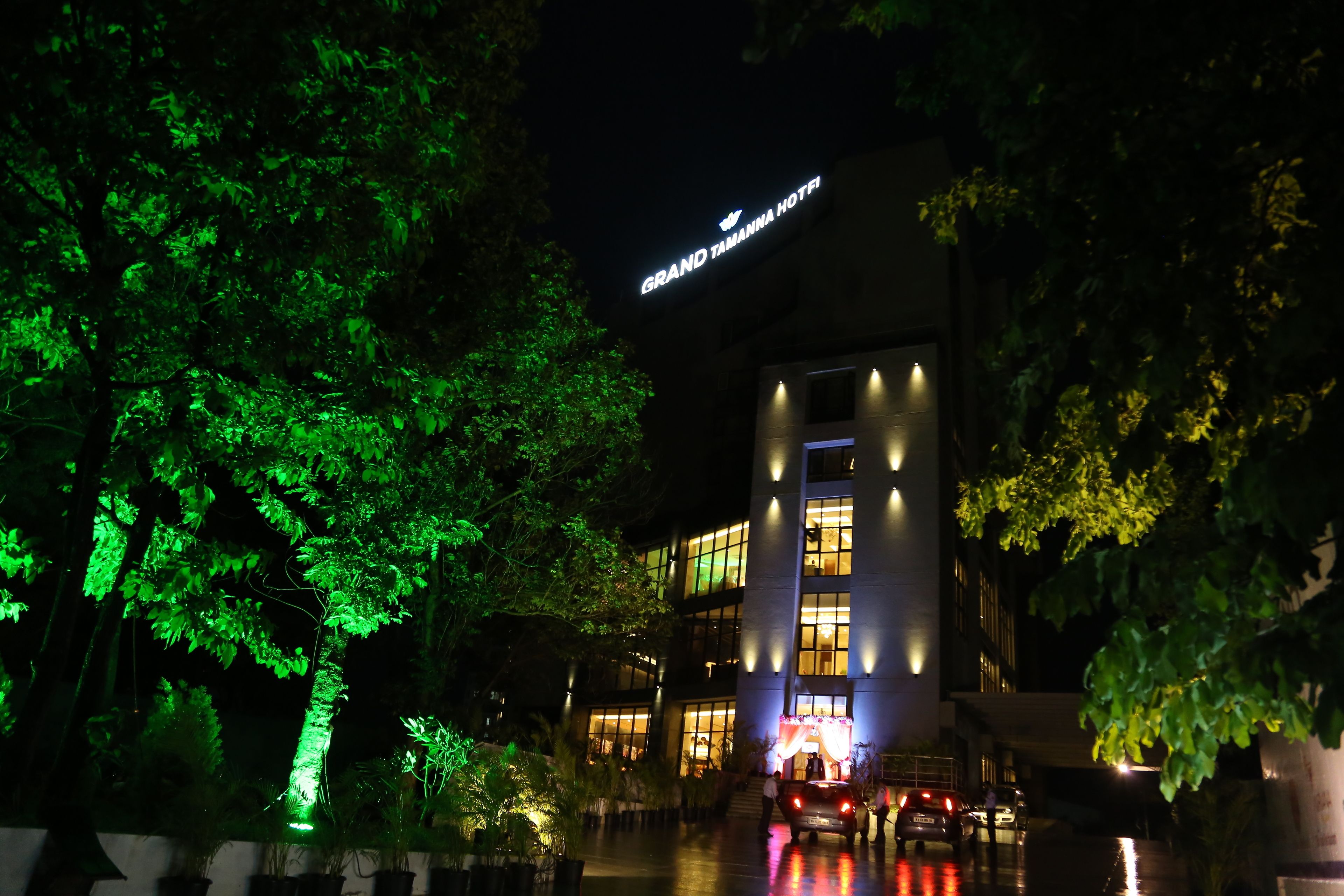 A hotel with a sign reading "Grand Tamanna Hotel" at night.