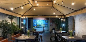 An indoor dining area with tables and chairs, a large mural on the back wall, and hanging lights. - MonteCristoHotel (Arequipa)