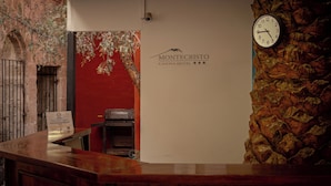Una recepción con un reloj, una señalización para el Hotel Montecristo Casona y una pared de piedra.