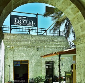 A hotel entrance with a sign for Casa de Montecristo Hotel, a stone facade, and a covered entrance area. - MonteCristoHotel (Arequipa)