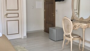 Una camera d'albergo con un letto, una scrivania con una sedia, uno specchio grande, una televisione fissata al muro e un armadio.