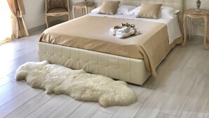 Un'ampia camera da letto con un grande letto, due comodini, una sedia e un quadro appeso al muro.