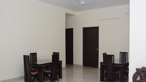 Una habitación amplia con una mesa de comedor y sillas, un ventilador de techo y una puerta.