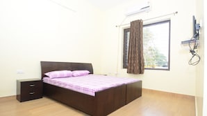 Un dormitorio con cama, mesita de noche, ventana con cortinas y equipo de aire acondicionado.
