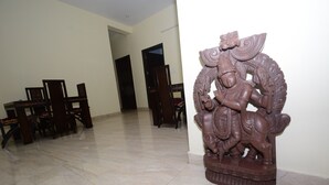 Una habitación con comedor que incluye una mesa y sillas de madera, una escultura decorativa y piso de baldosas.