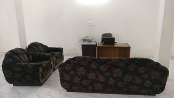 A room with two sofas, a wooden desk, and a laptop.