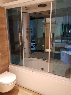Un baño moderno con ducha envuelta en vidrio, inodoro y bañera.