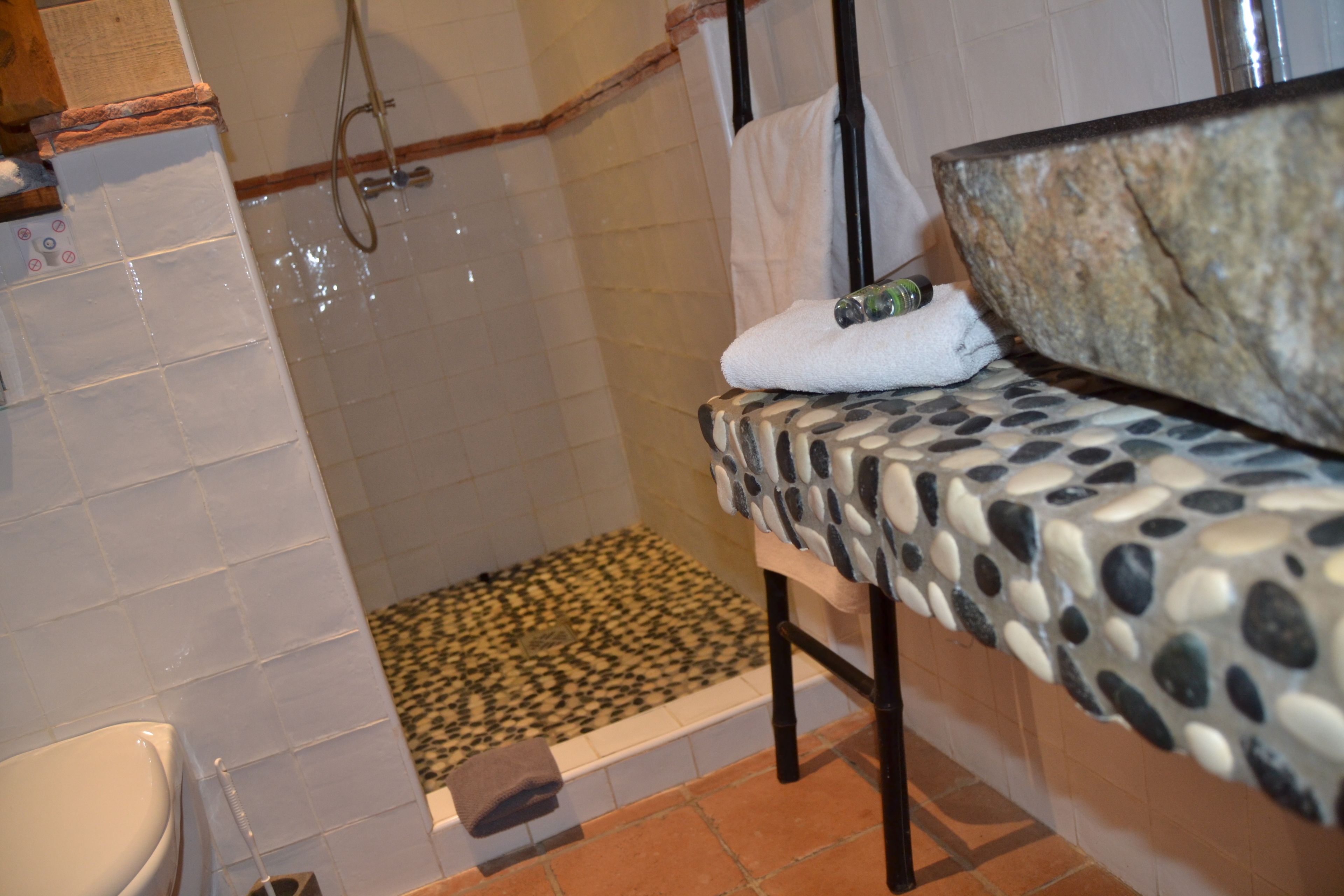 Un baño con ducha, inodoro y cama con cubrecama estampado.