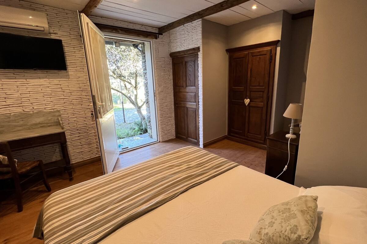 Une chambre à coucher avec un lit, un bureau, une chaise, une armoire et un téléviseur fixé au mur.