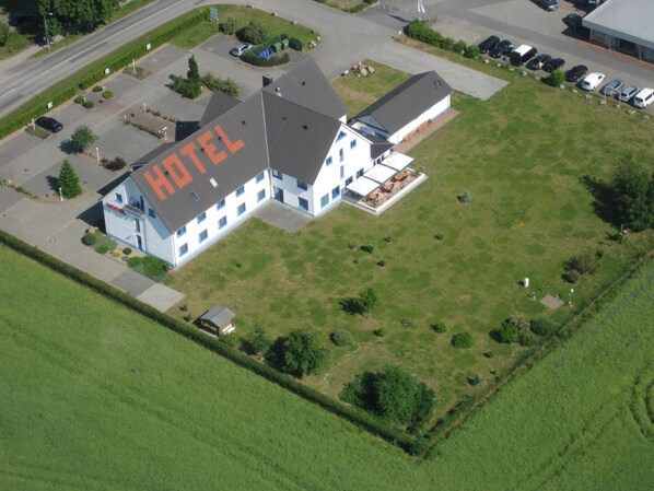 An aerial view of a hotel with a large sign reading "HOTEL" on the roof, surrounded by a parking lot and greenery. - Hotel Pommernland (Anklam)