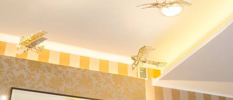 A ceiling with airplane decorations, a large mirror, and a potted orchid.