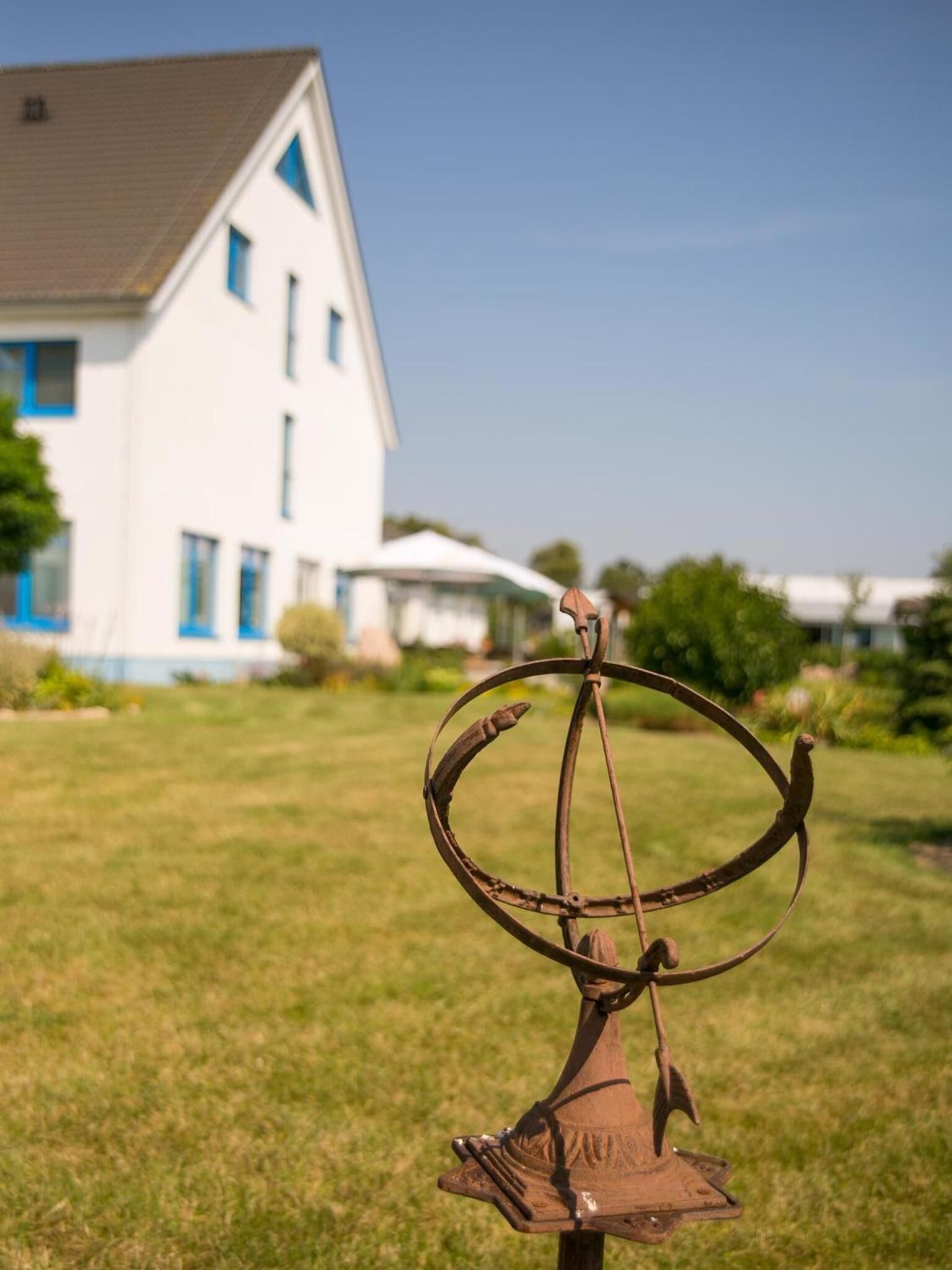 A metal sculpture in a grassy area with a house in the background.