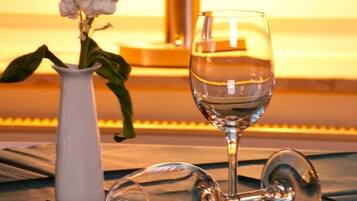 Una mesa con un vaso de agua, un florero con flores y una lámpara.