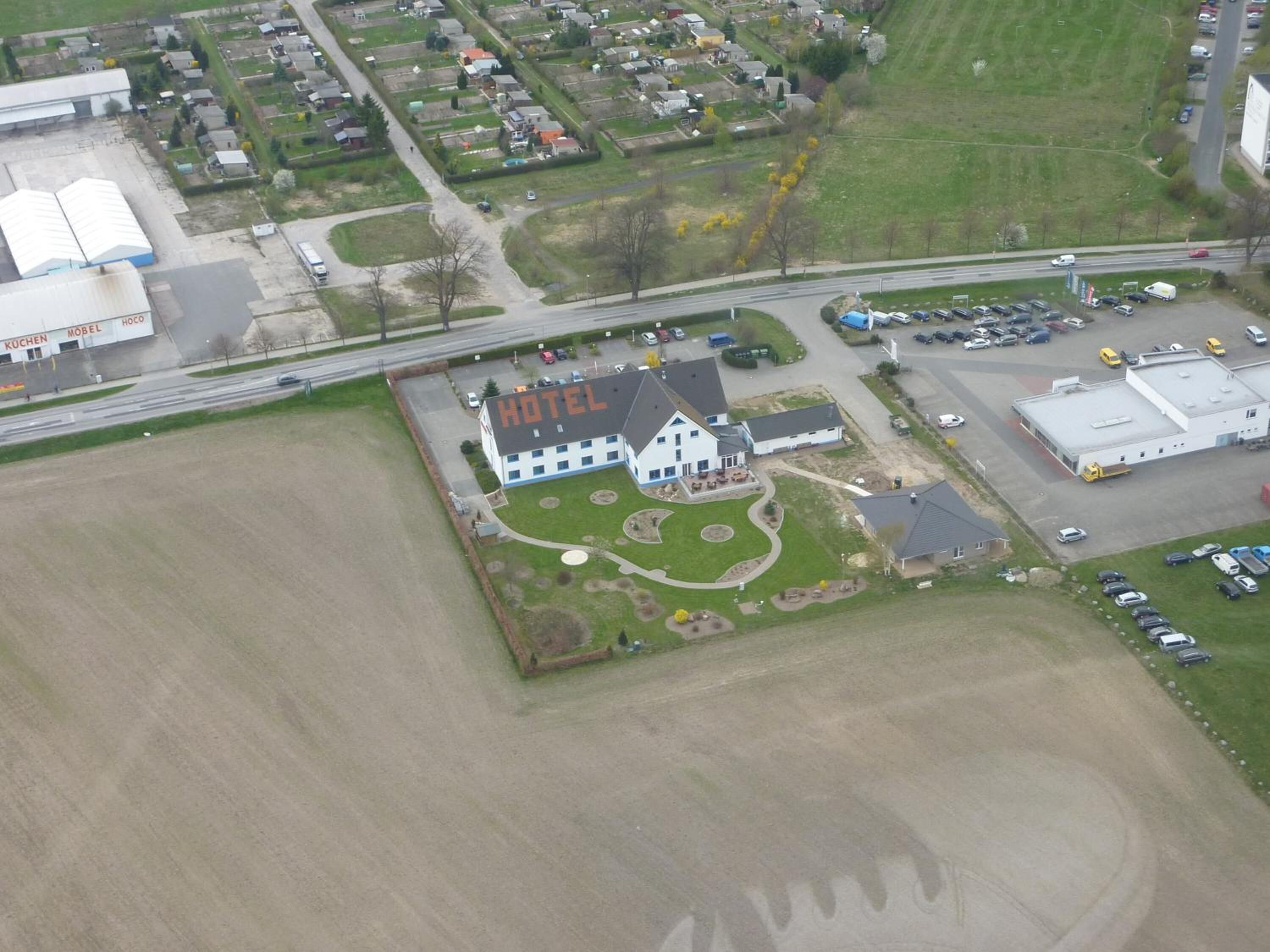 An aerial view of a hotel with a large building labeled "HOTEL" in the center, surrounded by a well-maintained lawn and parking area.
