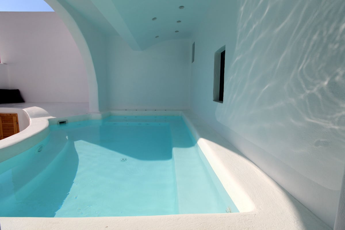 Una pequeña piscina rodeada, con interior blanco y superficie de agua azul transparente.