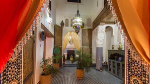 A hallway with patterned tile flooring, a chandelier, potted plants, and traditional decor. - Riad Sanaa Rose (Fes)