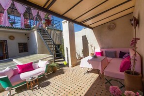 Un espacio de estar al aire libre cubierto con un sofá, una mesa y una escalera que lleva a un nivel superior.