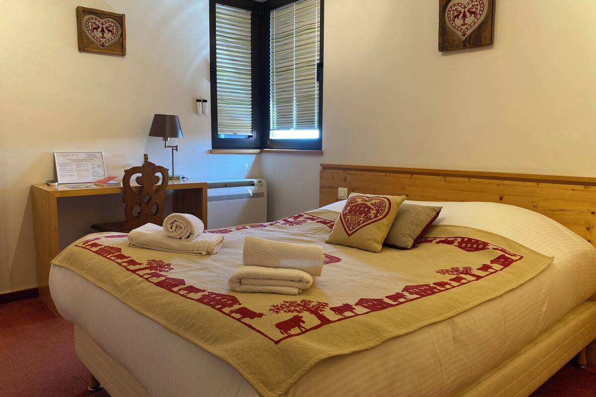 A neatly made bed with a decorative bedspread, a bedside table with a lamp, and a window with blinds.