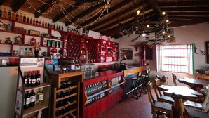 Eine Bar mit Regalen voller Flaschen, einer Theke und Holzmöbeln.