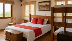Ein Schlafzimmer mit einem hölzernen Bett, einem Nachttisch, einer Holzkiste und einem Etagenbett.