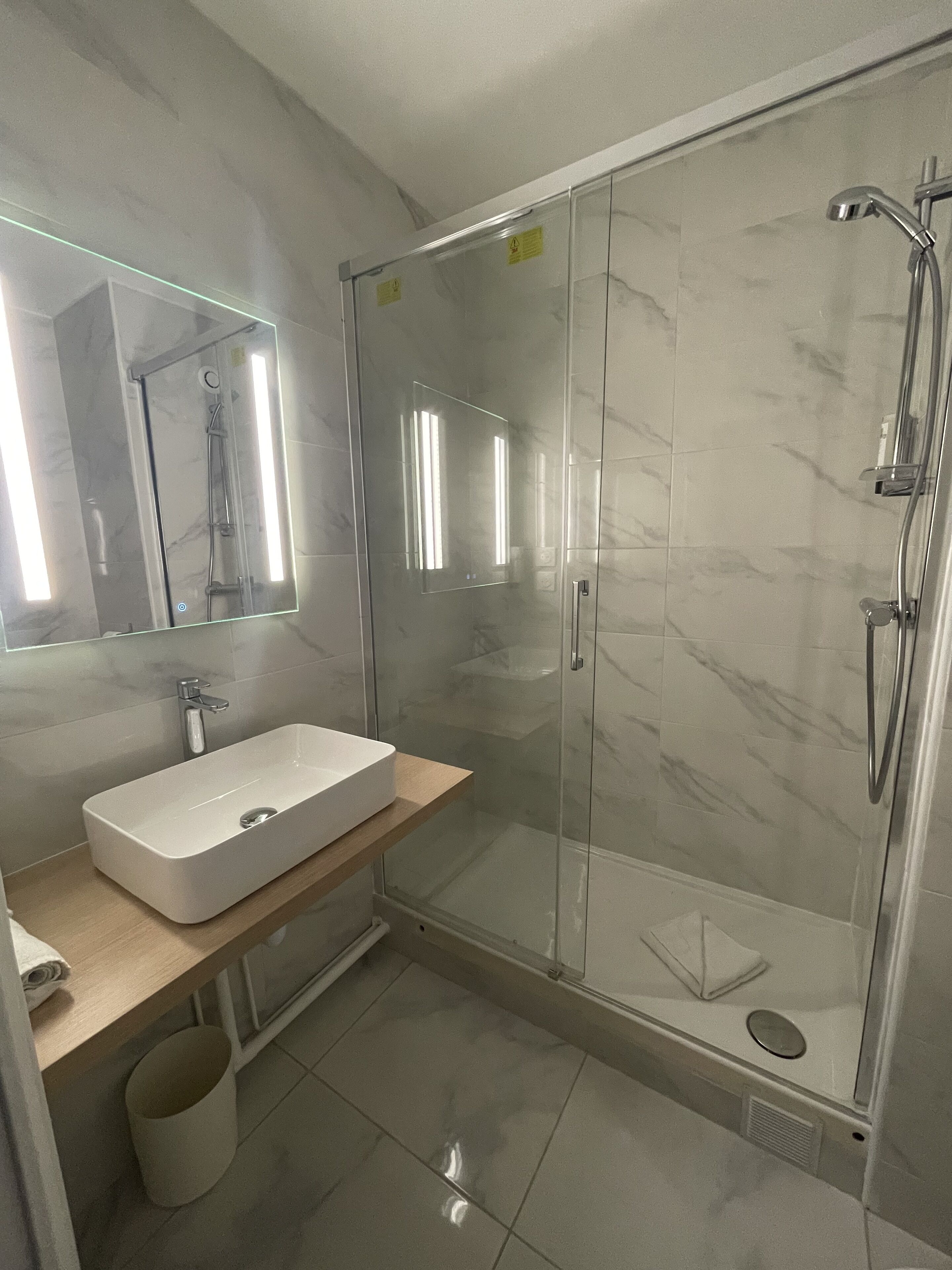 A modern bathroom with a glass-enclosed shower, a white sink, and a mirror above the sink.