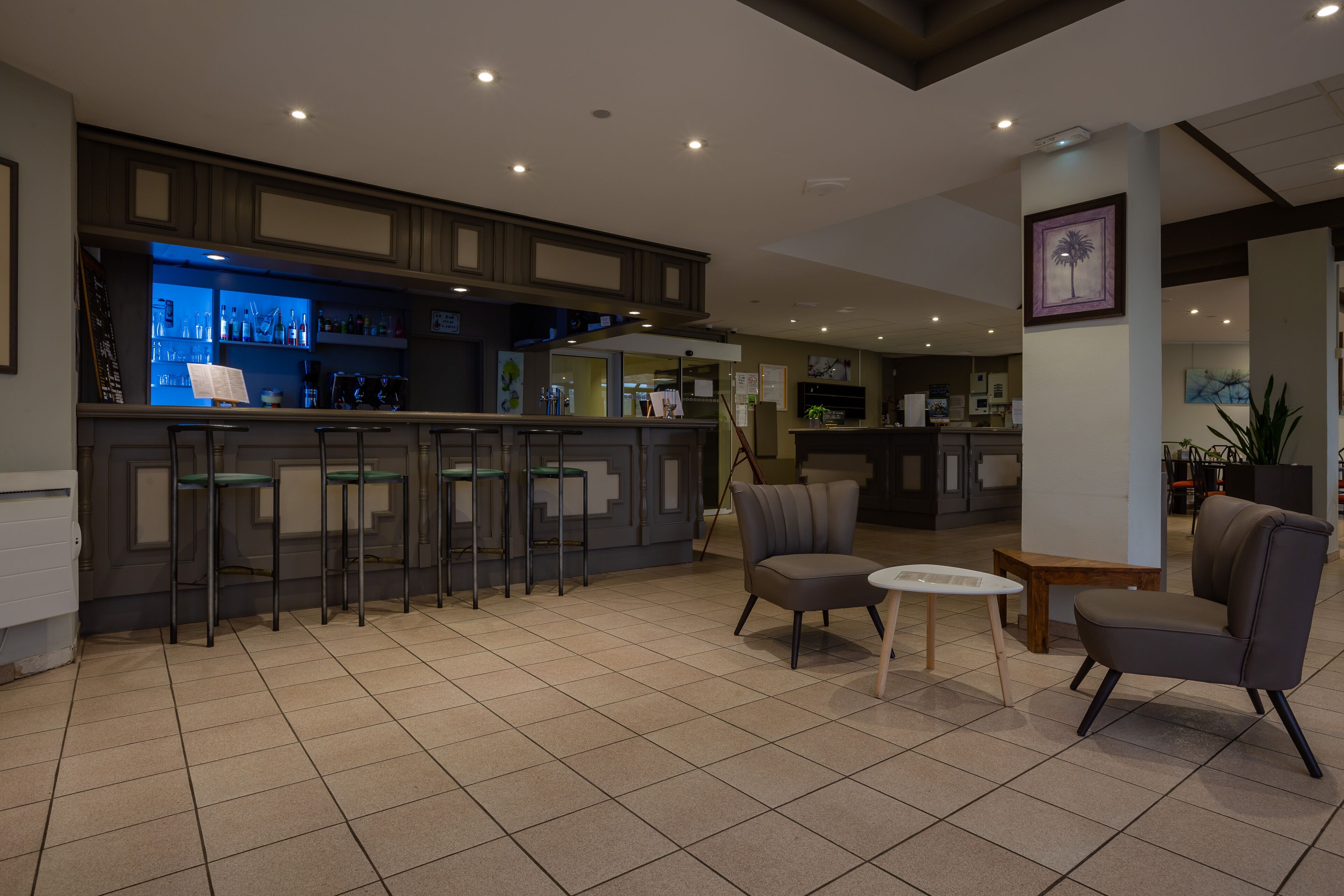 A modern bar area with a counter, stools, and a seating area with two chairs and a small table.