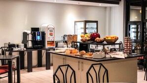 A modern kitchen area with a coffee machine, fruit bowls, and a variety of breakfast items. - Cit' Hôtel la Pyramide (Romorantin-Lanthenay)