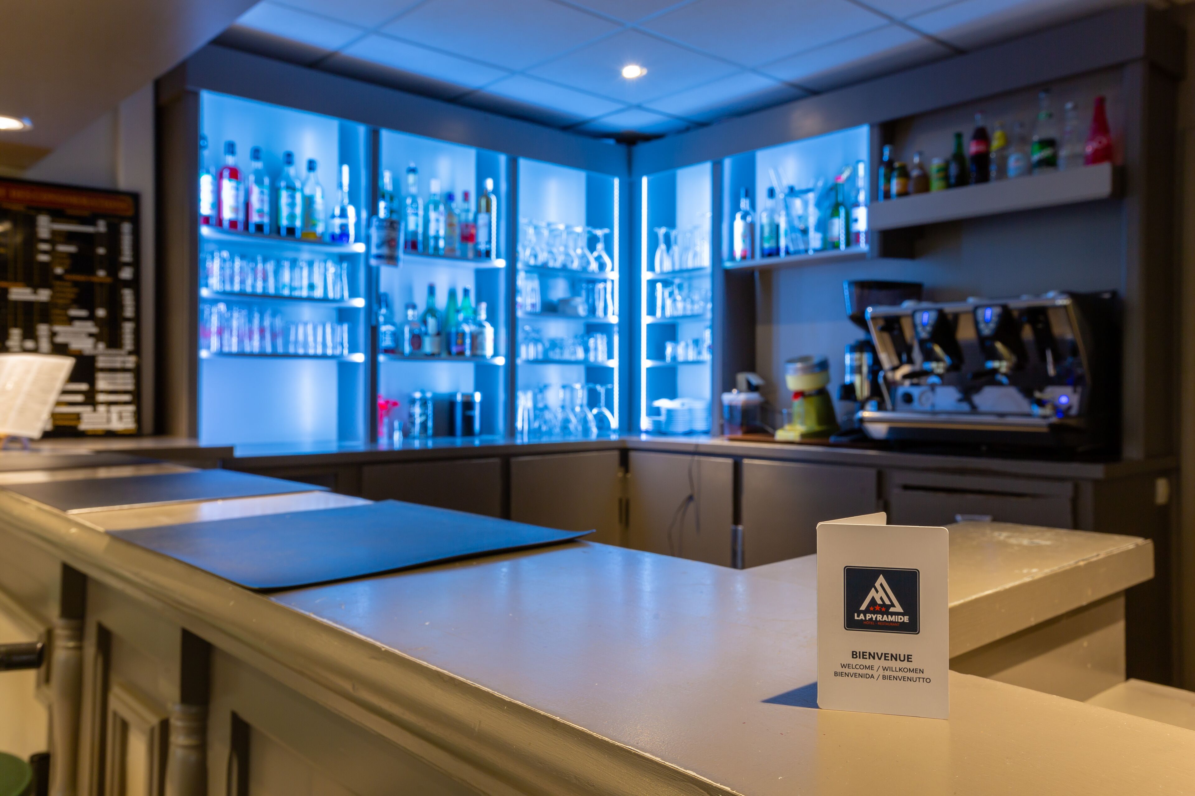 Eine Bar mit Regalen voller Spirituosenflaschen, einem Willkommensschild und Barbereitungen.