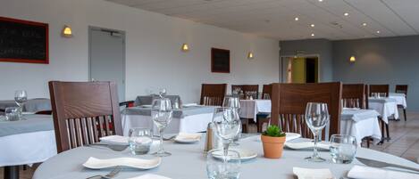 A dining area with tables set for two, each with cutlery, plates, and glasses.