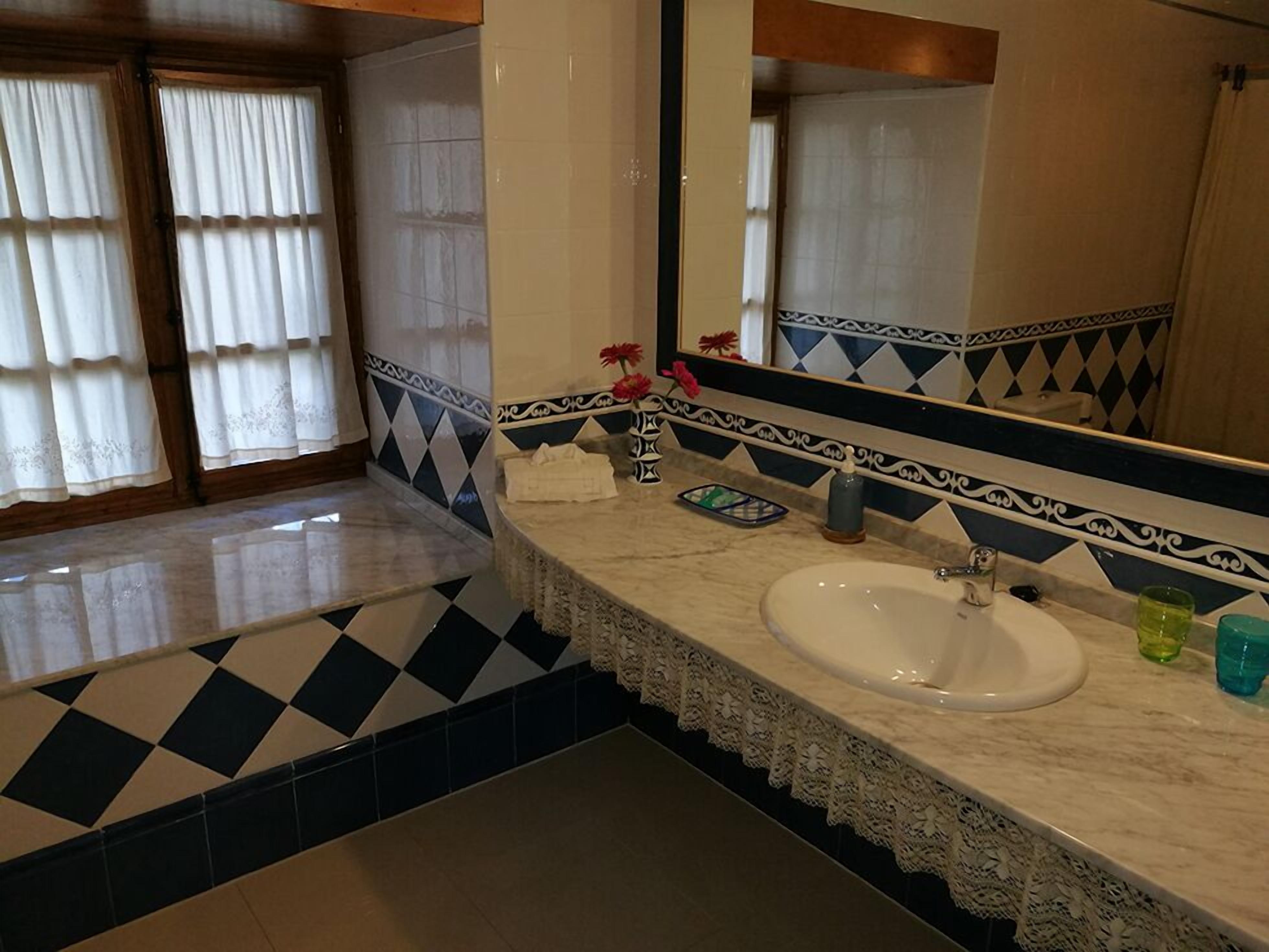 A bathroom with a white sink, a mirror, and a patterned floor.