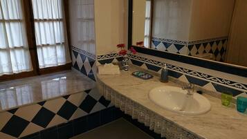 A bathroom with a white sink, a mirror, and a patterned floor.