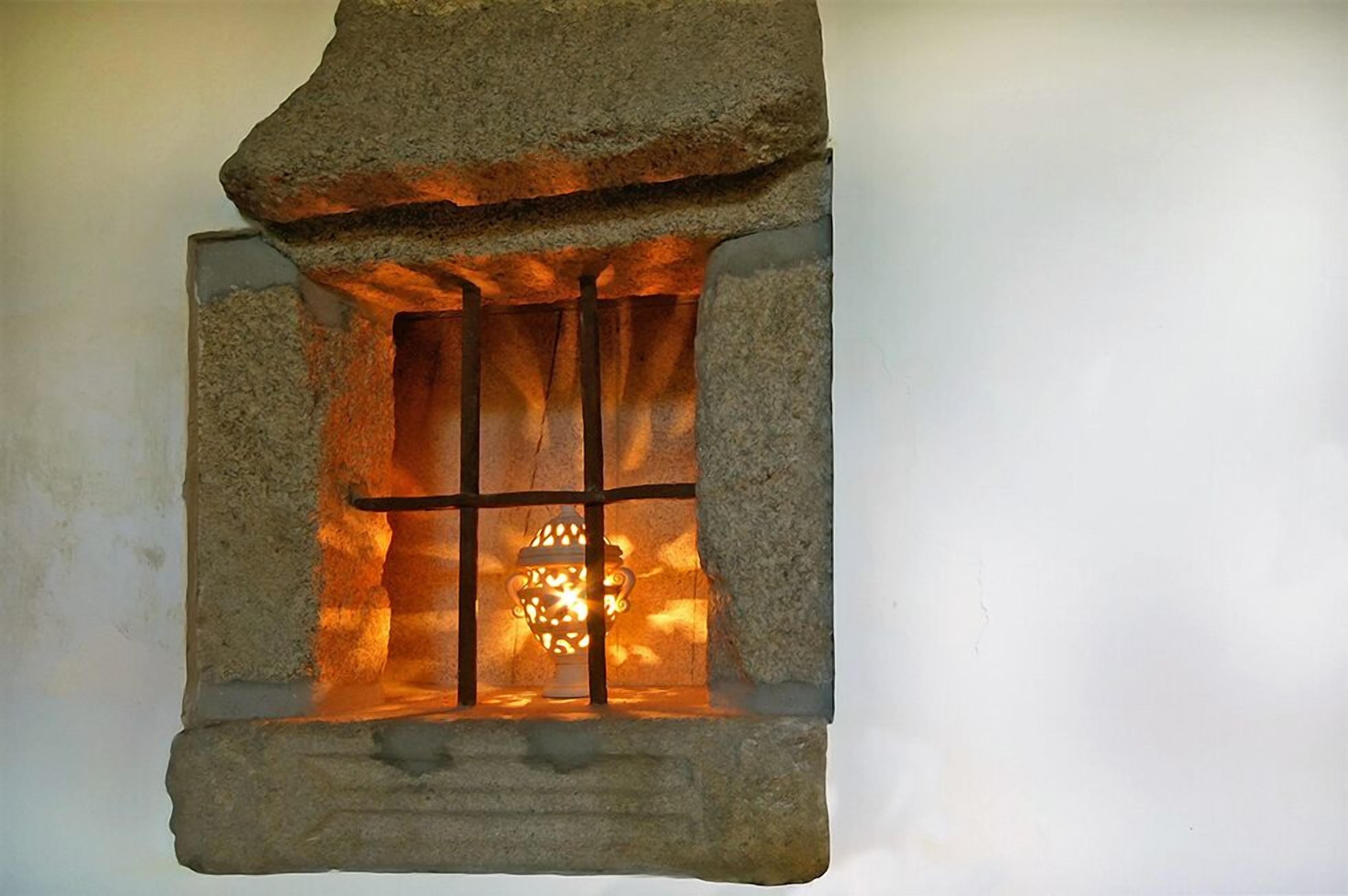 A stone fireplace with a metal grate and a decorative lantern inside.