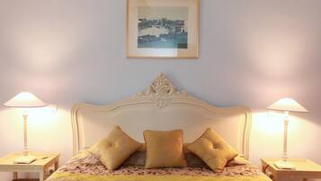 A bedroom with a bed, two bedside lamps, a framed picture on the wall, and a decorative headboard.