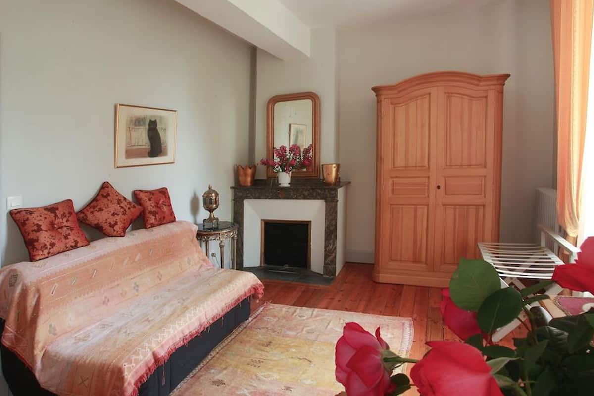 A bedroom with a bed, a fireplace, a wardrobe, and a window with curtains.